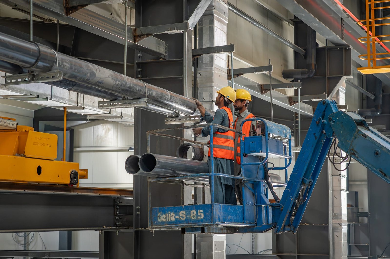 Crew installing overhead HVAC ductwork from a boom lift